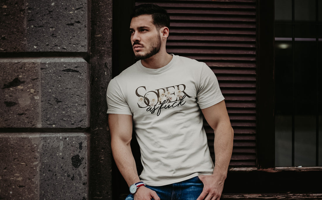 Muscular young man in a "Sober As Fuck" T-shirt highlights the hidden struggles of sobriety in the queer community. Moody, Booty Apparel supports empowerment.